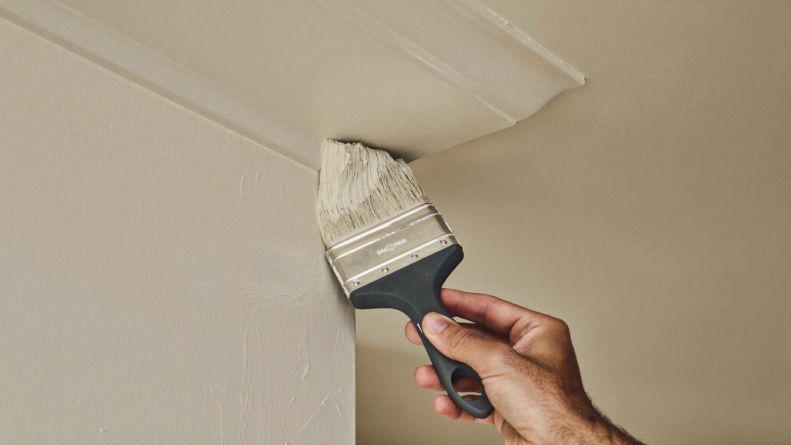 Painter cutting a crisp line along ceiling trim
